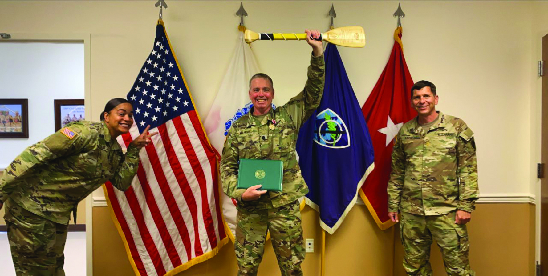 Members of team 350th CACOM OCJA briefly remove their masks, while maintaining social distance, to wish LTC Mark Milhiser a safe departure from Pensacola, Florida, and arrival at the Pentagon. Outgoing CJA, LTC Milhiser poses with the much coveted, and well-earned, 350th CACOM paddle. He is accompanied in the photo by SSG Jacqueline Reyes (left) and MAJ Chris Kinslow (right).